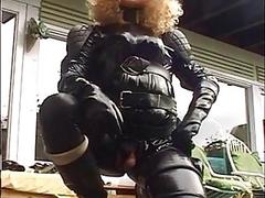 Shemale in a full leather outfit plays with her dick